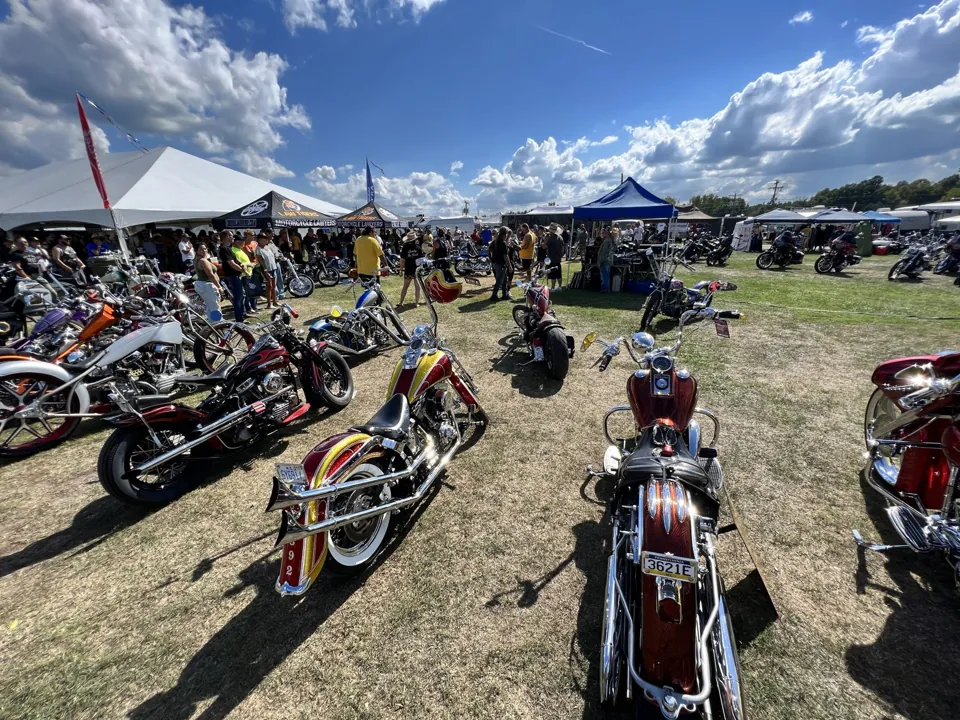 Custom motorcycles lined up in the field at a rally
