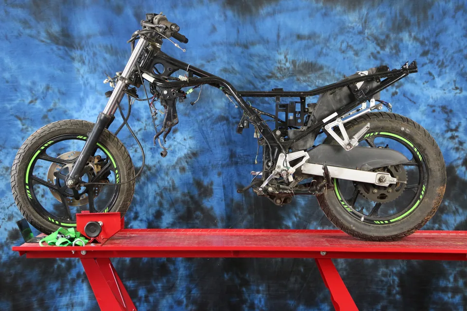 A Kawasaki Ninja 250 on a lift with its engine and bodywork removed, the bare frame ready for conversion.