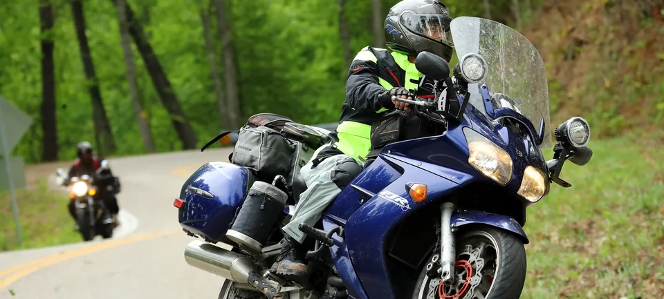 Wendy Crockett inclinando su Yamaha FJR1300 en una curva en el Tail of the Dragon, con otro motociclista detrás de ella.